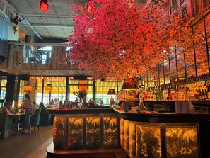 A bar area with a counter, seating, and a decorative tree with pink flowers. - House Hotel Belfast (Belfast)