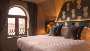 A hotel room with a large bed, a window with curtains, a wall with pineapple wall art, and a lamp on the nightstand. - House Hotel Belfast (Belfast)