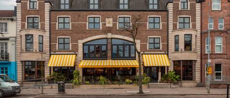 A multi-story building with a central arched entrance and yellow-striped awnings.