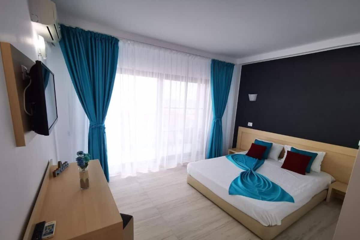 Ein Hotelzimmer mit Bett, Schreibtisch, Fernseher und einem Fenster mit Vorhängen.