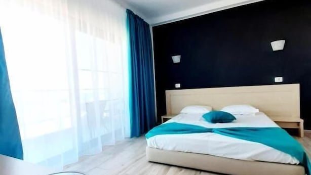Une chambre d’hôtel avec un lit, une table de chevet, une fenêtre avec des rideaux et une vue sur l’extérieur.