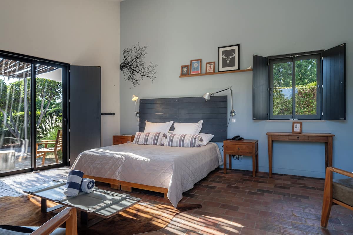 Een slaapkamer met een bed, nachtkastjes, een bureau, een stoel en uitzicht op het landschap.