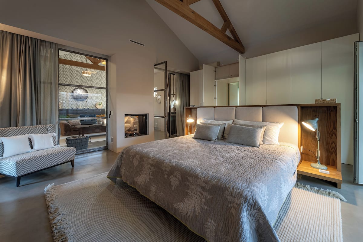 Een moderne slaapkamer met een groot bed, een bank, een bureau en een kledingkast.