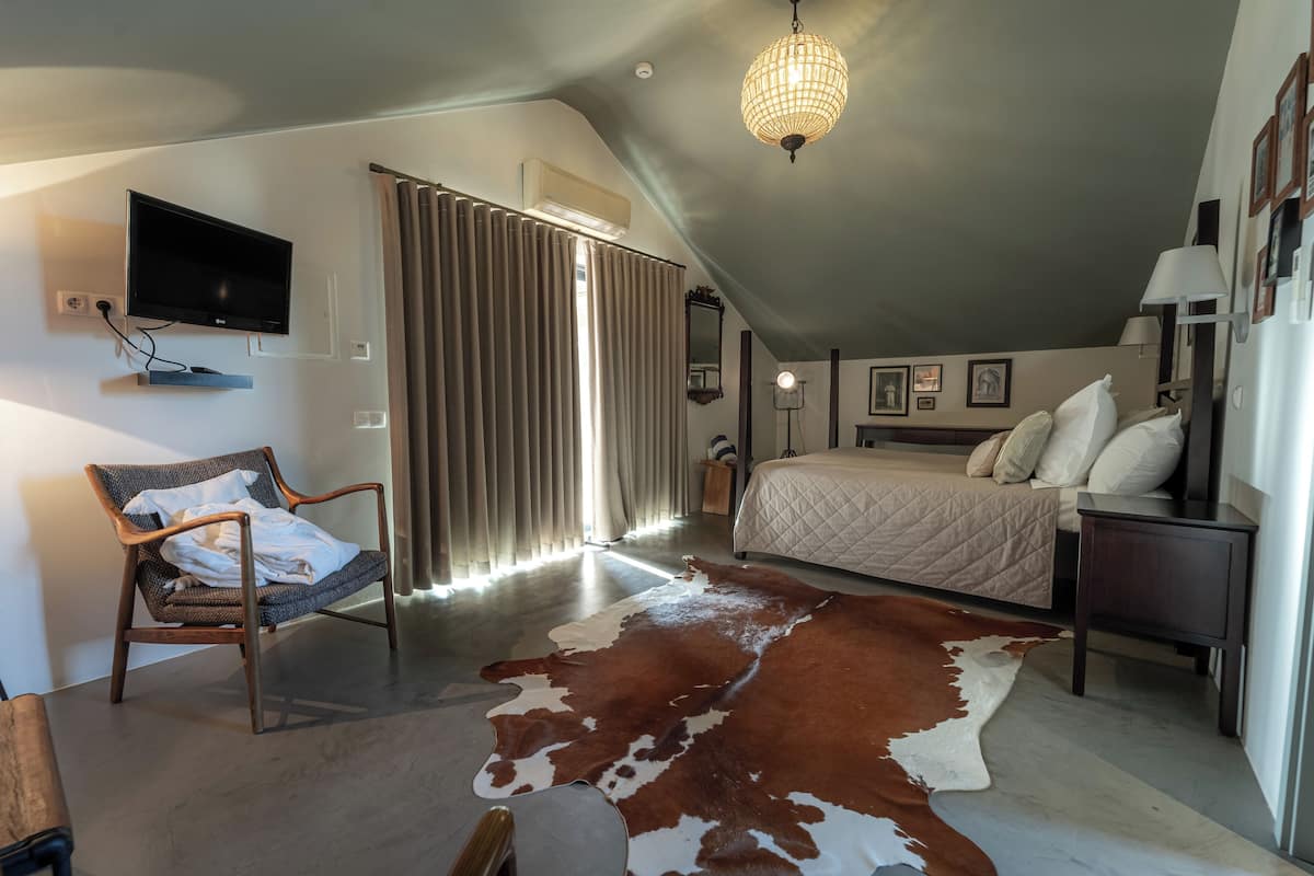 Een slaapkamer met een groot bed, een stoel, een televisie en een plafondlamp.