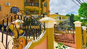 A multi-story building with a yellow facade, balconies, and ornate black wrought iron gates. - Eagles Nest (Montego Bay)