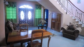 A dining area with a wooden table and chairs, a sofa, and a staircase leading to an upper floor. - Eagles Nest (Montego Bay)