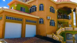A large, two-story house with a red roof, multiple windows, and a covered porch. - Eagles Nest (Montego Bay)