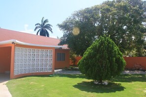 A house with a red roof, a white fence, and a green lawn.