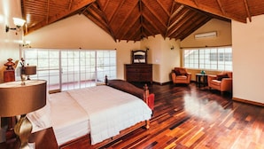 A spacious bedroom with a large bed, wooden flooring, a sloped ceiling, and large windows. - Paradise  Beach Front Apartment (Discovery Bay)