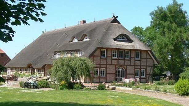 Une grande maison de style traditionnel, dotée d’un toit à forte pente, de nombreuses fenêtres et d’un jardin bien entretenu.