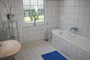 A bathroom with a sink, bathtub, and a window with a view of the outdoors. - Rental - Rügen-Fewo 207 (Rappin)