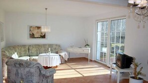 Un salon avec un canapé, une petite table, un téléviseur et une plante en pot.