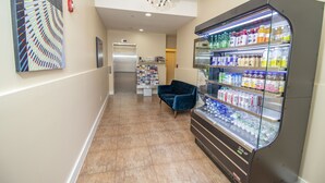 A hallway with a vending machine stocked with beverages, a blue chair, and a refrigerator in the background. - Canal Loft Hotel (New York)