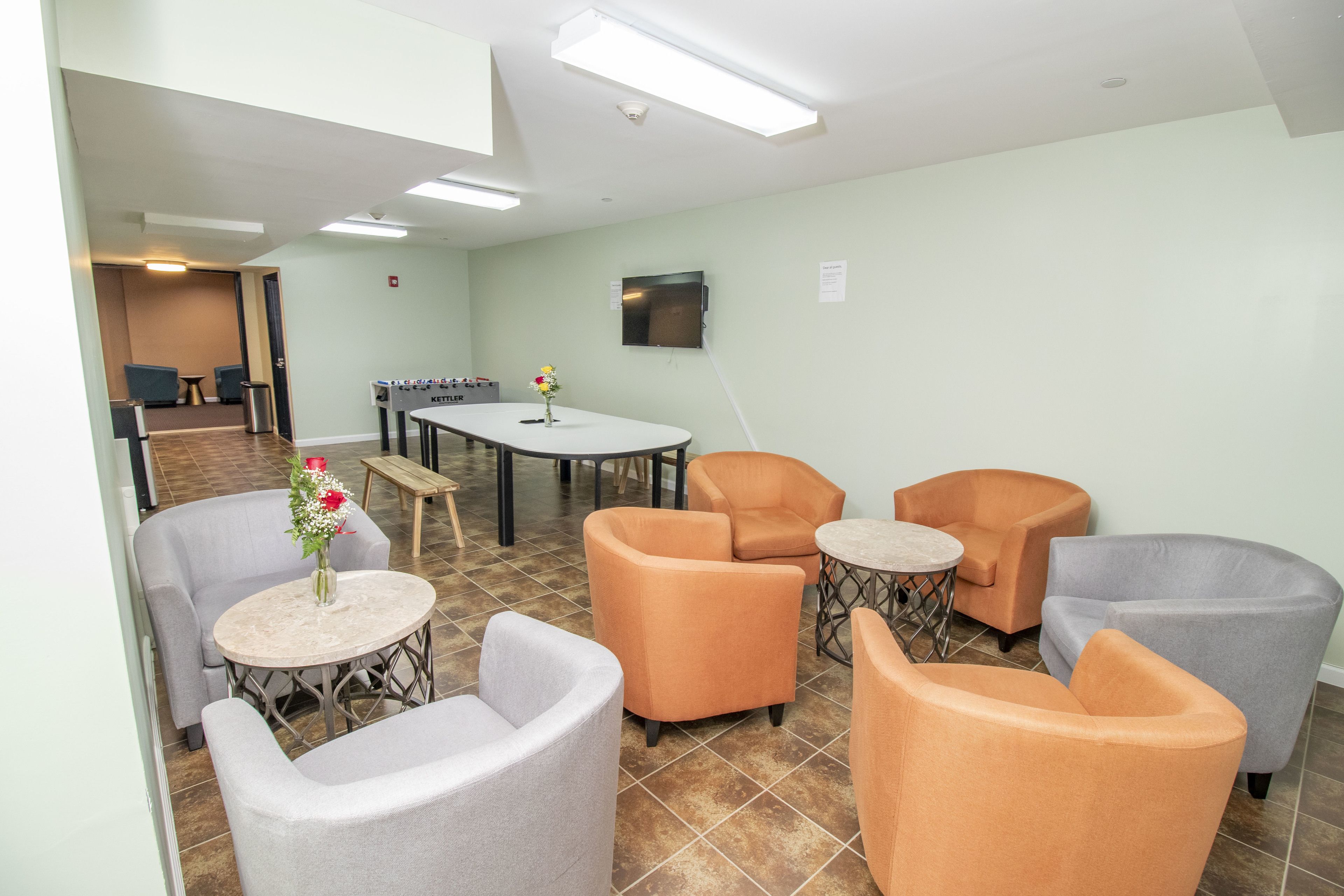 Een hotellobby met een zithoek, met fauteuils, een ronde tafel, een bijzettafeltje en een bloevas.