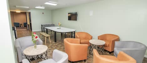 Een hotellobby met een zithoek, met fauteuils, een ronde tafel, een bijzettafeltje en een bloevas.