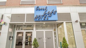 The exterior of Canal Loft Hotel with a blue sign, double doors, and two potted plants in front. - Canal Loft Hotel (New York)