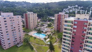 A high-rise residential building with multiple balconies, a central courtyard with a swimming pool, and surrounding greenery. - Beach Condo at Turtle Towers (Ocho Rios)