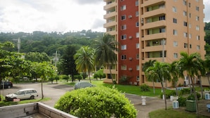 A multi-story residential building with balconies, surrounded by greenery and a parking area. - Beach Condo at Turtle Towers (Ocho Rios)