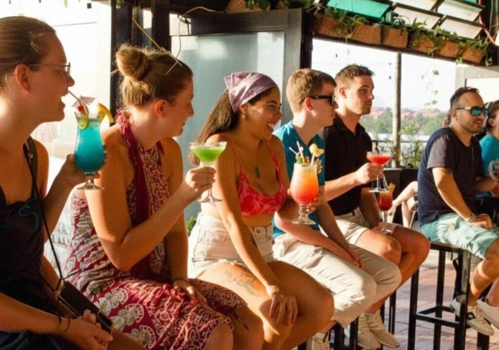 A group of people seated at an outdoor bar area with drinks, overlooking a scenic view.