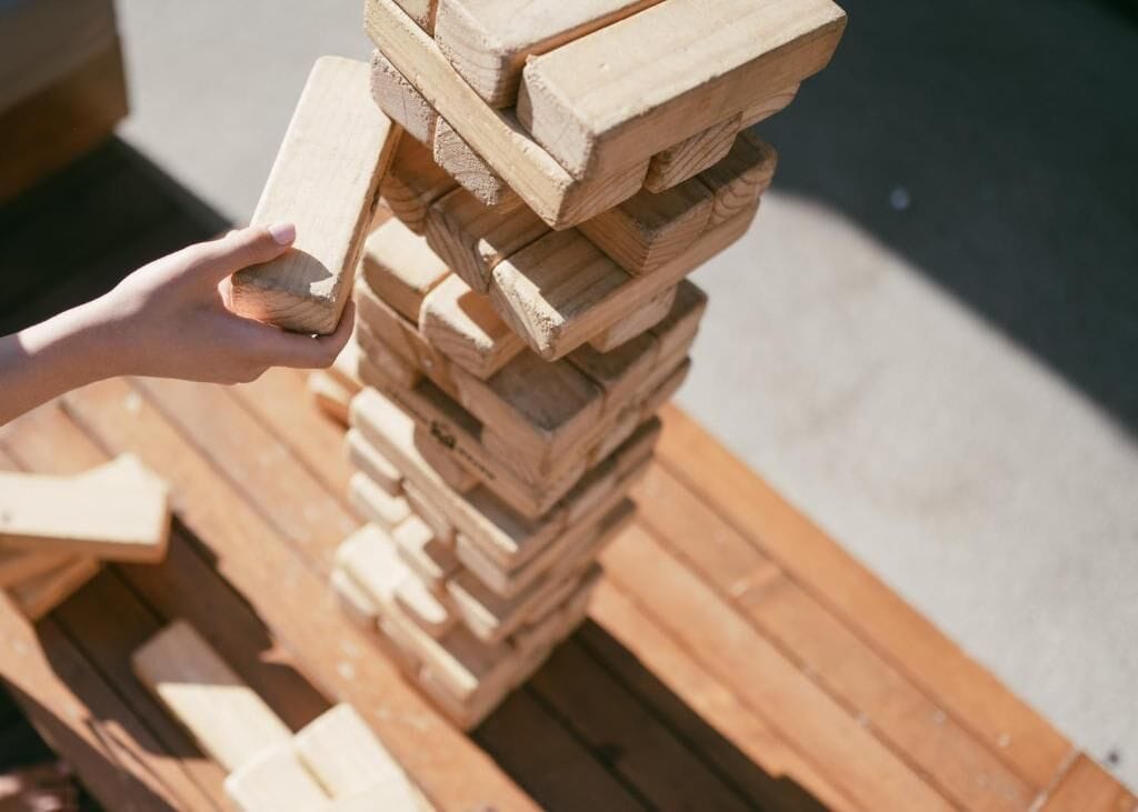 A hand holding a wooden block, stacked on top of other wooden blocks on a pallet.