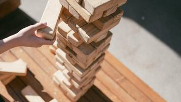 A hand holding a wooden block, stacked on top of other wooden blocks on a pallet.