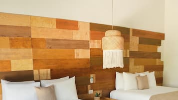 Habitación de hotel con dos camas, cabecero de madera, lámpara colgante, mesitas de noche y una pequeña planta en maceta.