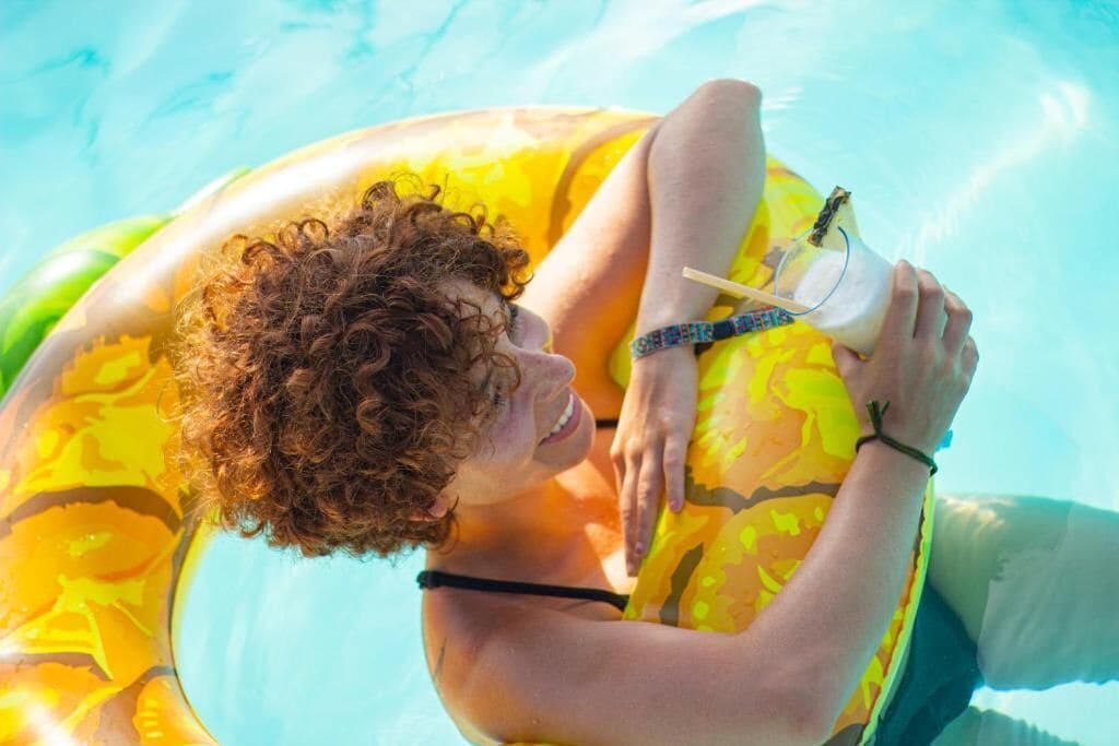 A person reclining on a yellow inflatable pool float in a swimming pool.