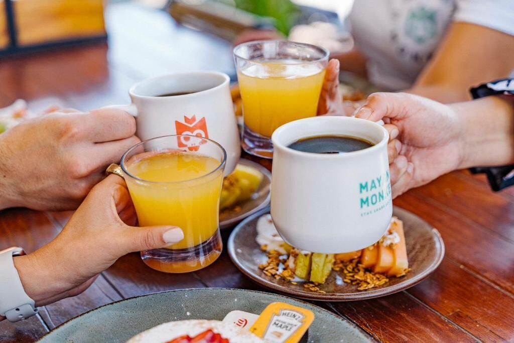 A breakfast setting with two mugs and a glass of orange juice on a table.