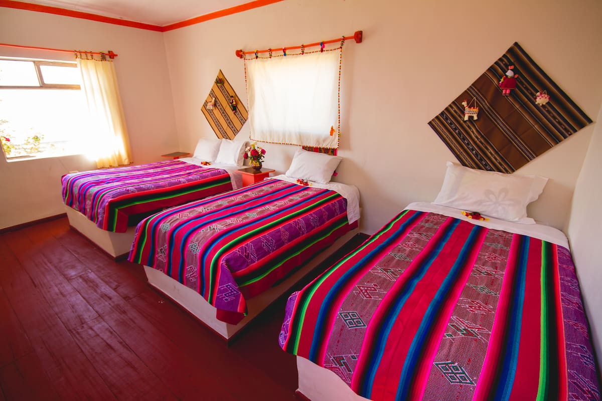 A hotel room with two beds, each with colorful, patterned bedspreads.