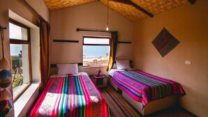 Een kamer met twee bedden, een groot raam en uitzicht, en een geweven plafond.
