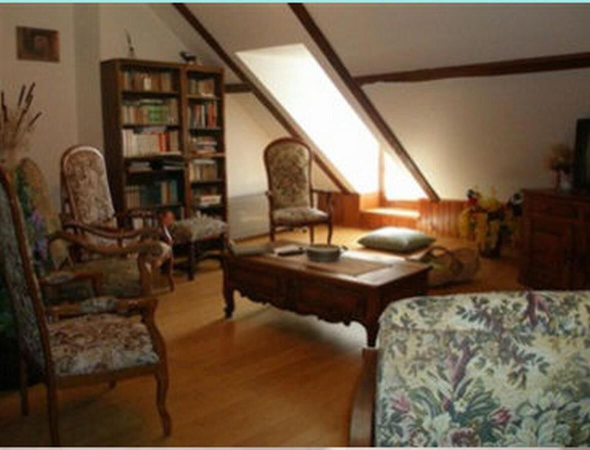 Acogedor dormitorio en ático con muebles de madera, una estantería y techo inclinado.