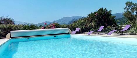 Una piscina al aire libre, sillones reclinables de piscina