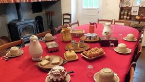 A dining table set with various food items and tea sets, surrounded by chairs. - Chambres d'hôtes Anousta (Loubajac)