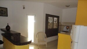 A kitchen with a yellow countertop, a white refrigerator, and a chair. - Residence Yoff Toundou Bya (Dakar)