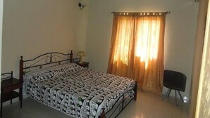 A bedroom with a bed, a chair, a nightstand, and a hanging light fixture. - Residence Yoff Toundou Bya (Dakar)