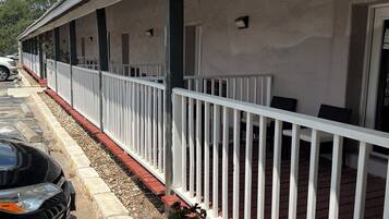 A long, single-story building with a covered outdoor area, white railings, and a paved walkway.