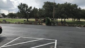 A parking lot with marked spaces and a playground in the background.