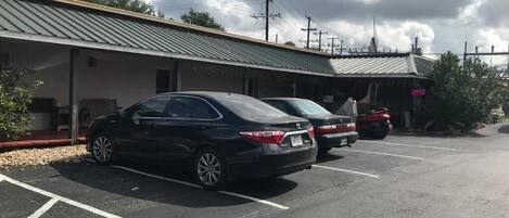 Un parking où sont garées deux voitures devant un bâtiment doté d’un toit végétalisé et d’une enseigne indiquant « OUVERT ».