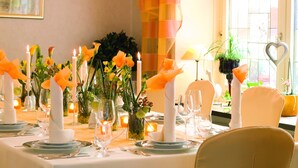 A dining table set with candles, flowers, and glassware, with a chandelier above. - Wittlers Hotel (Ratzeburg)