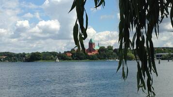 A calm lake with a church and sailboat in the distance.