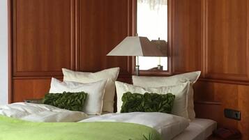 Una habitación de hotel con una cama grande, dos mesitas de noche, un espejo y una planta en maceta.