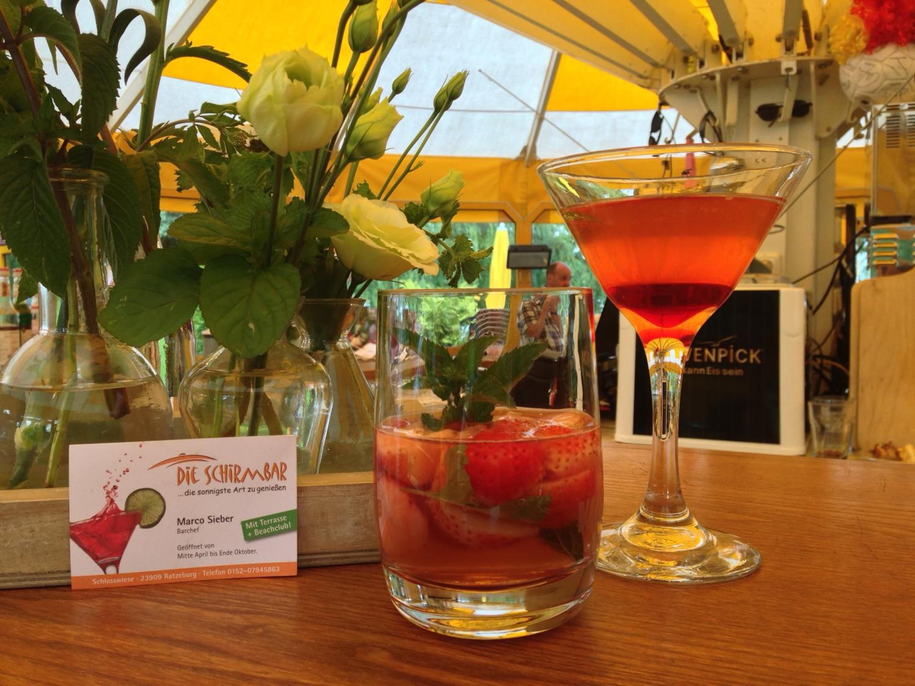 Un bar con una copa de martini, una bebida con fresas y un menú.