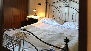 Een slaapkamer met een houten plafond, een metalen bedframe, een nachtkastje met een lamp en een kledingkast.