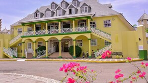 A yellow building with a green and white staircase leading to a covered entrance. - Sandy Shores at Sandcastles (Ocho Rios)