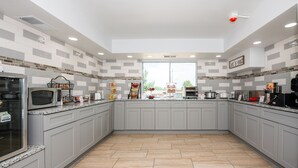 Eine moderne Küche mit grauen Schränken, einer Granitarbeitsplatte und verschiedenen Geräten, darunter eine Mikrowelle, ein Backofen und ein Toaster.