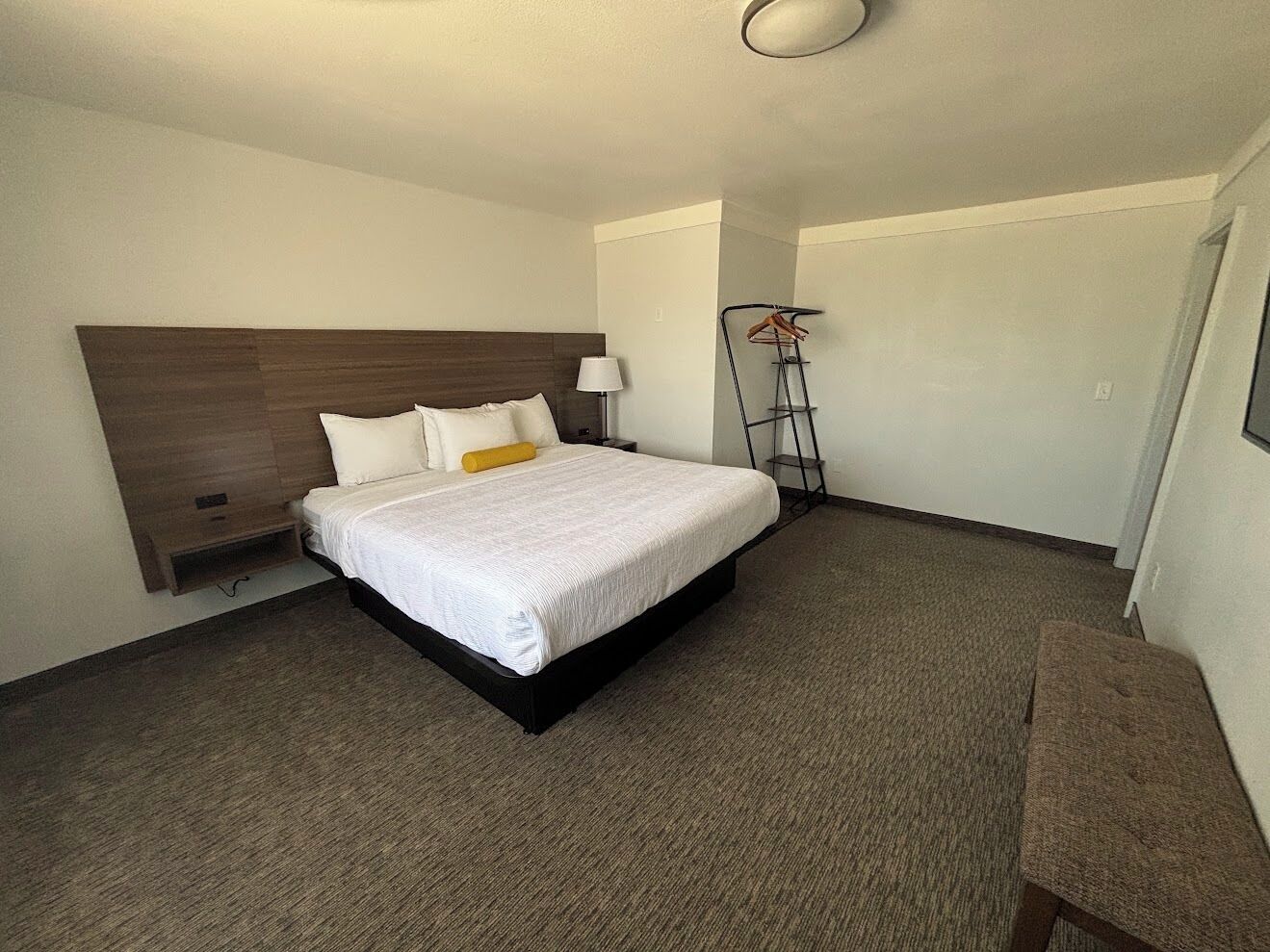 A hotel room with a large bed, a bedside table, a lamp, and a floor lamp.