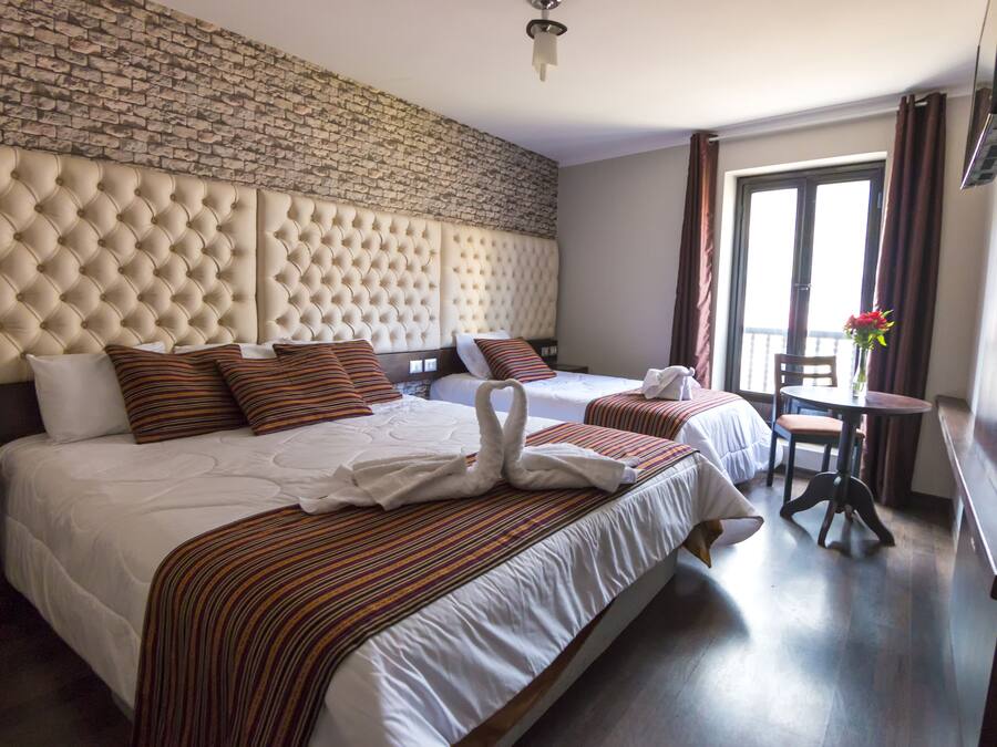 A hotel room with a large bed, a second bed, a dining table, and a view of the outdoors.