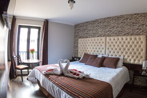 Habitación de hotel con una cama grande, una mesa de comedor, una silla y vistas al exterior.