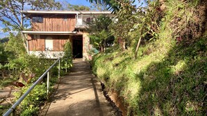 A pathway leading to a wooden building with a metal railing on one side. - Casa Alquimia Artes (Monteverde)