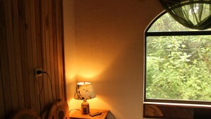 A wooden room with a window, a lamp, and a small table. - Casa Alquimia Artes (Monteverde)